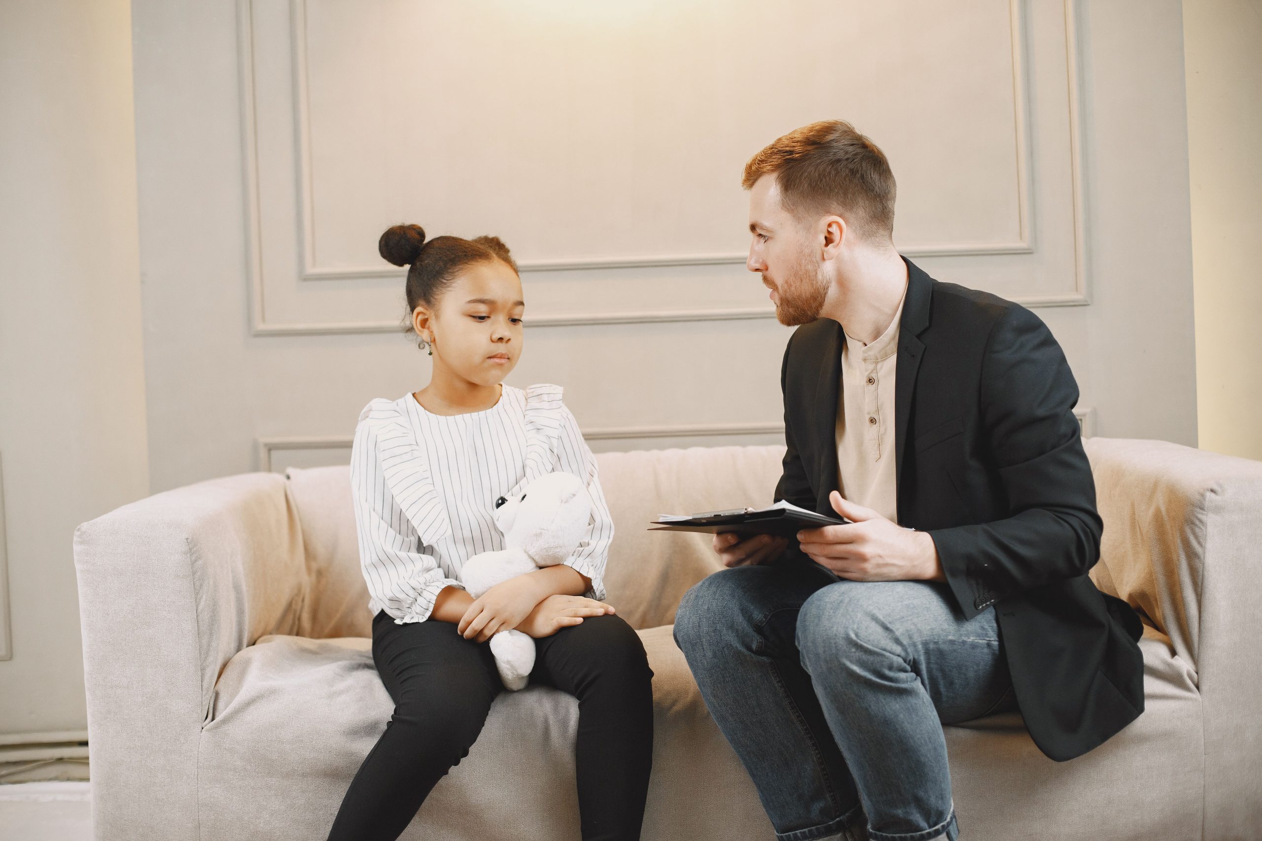evaluator talking to a girl holding a teddy bear