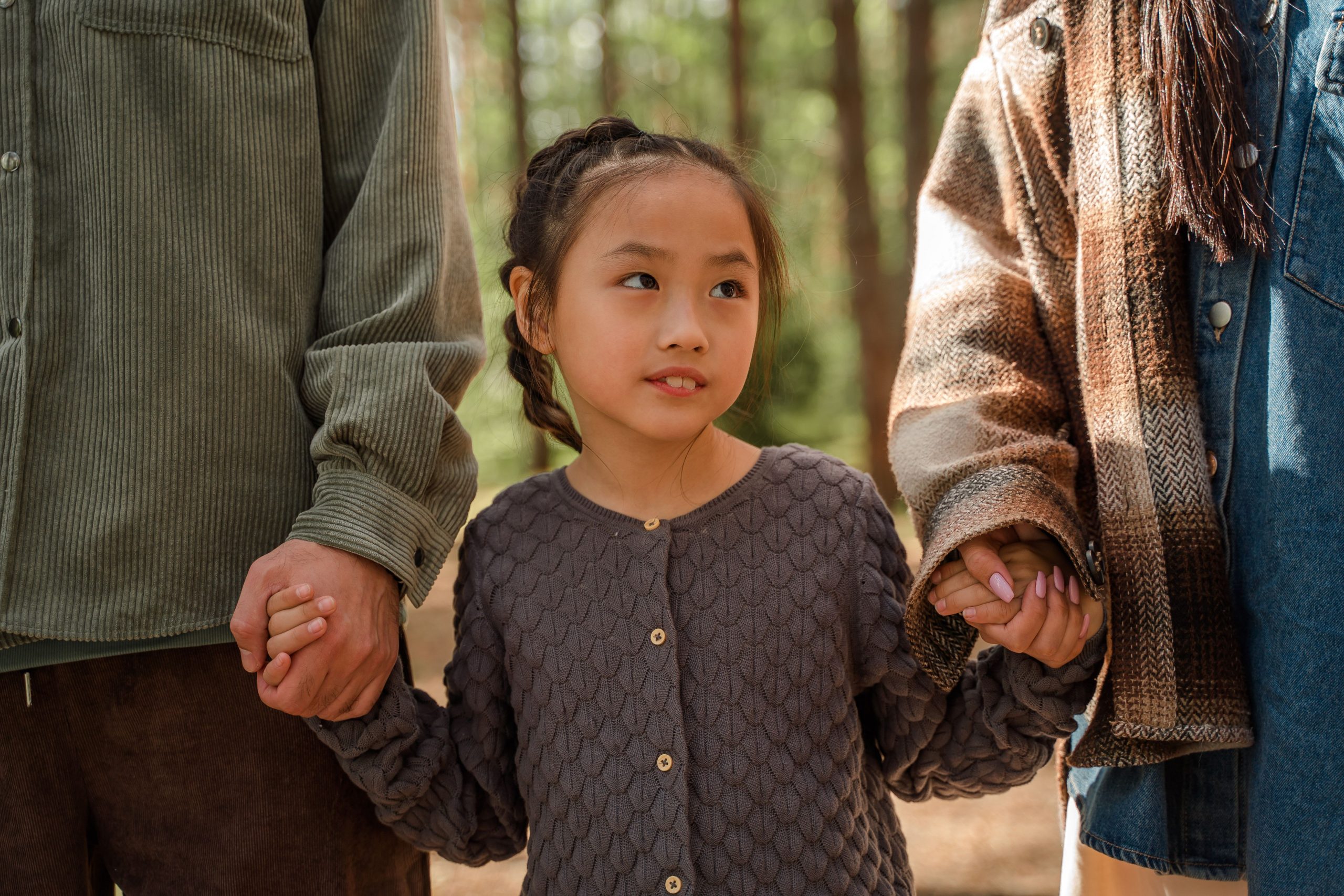 girl holding hands with her parents